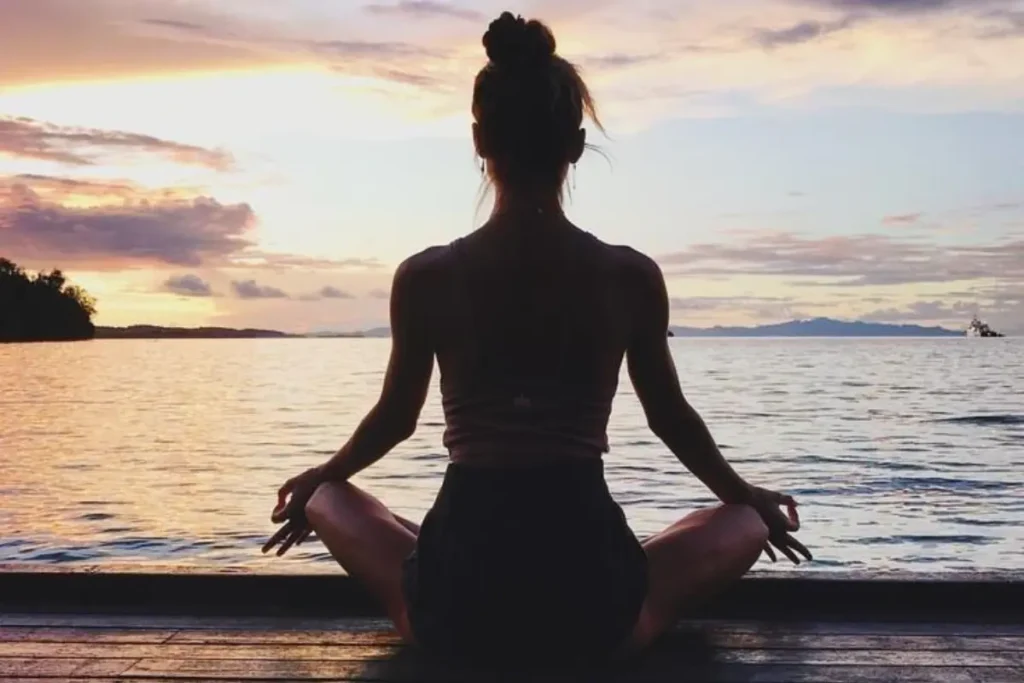 Mulher meditando na beira da praia