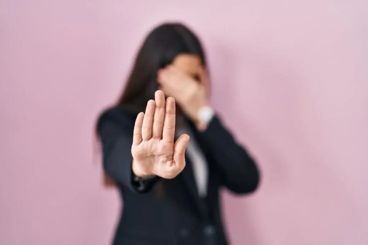 Bloqueios Emocionais 4 Passos para Reconquistar Sua Paz Interior - Mulher com uma mão no rosto e outra esticada para frente