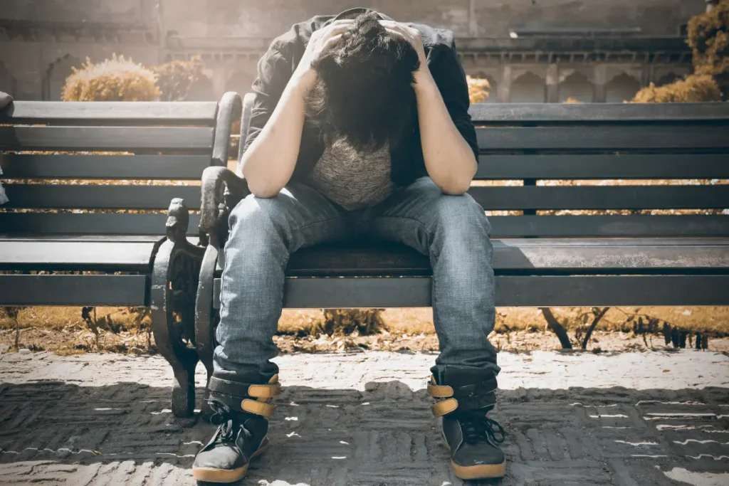 Homem triste sentado num banco de praça