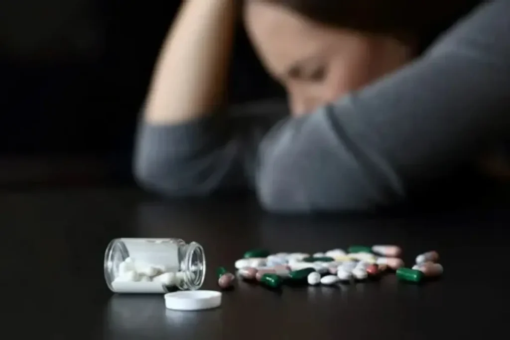 Mulher triste ao lado de muitos remédios