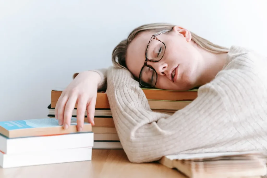 Mulher cansada dormindo em cima de uns livros