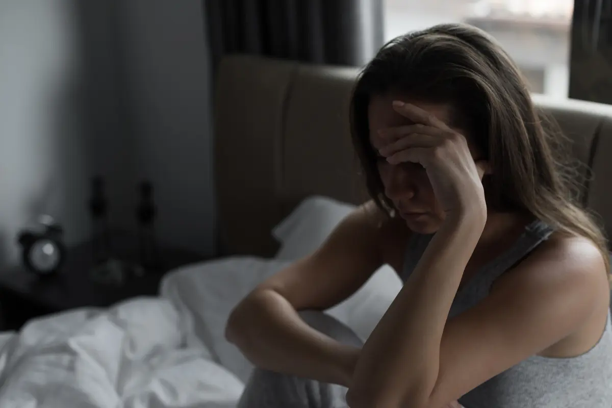 Mulher triste sentada na cama